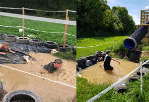 People splashing in an muddy assault course pool