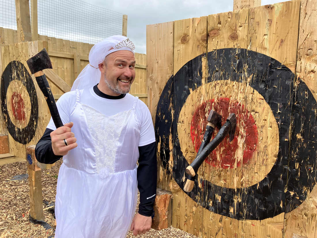Participant in celebration clothing beside an axe throwing target