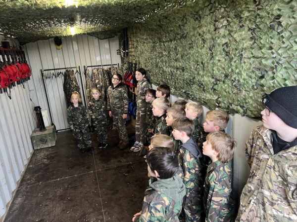 Children in camouflage overalls preparing for a laser tag session